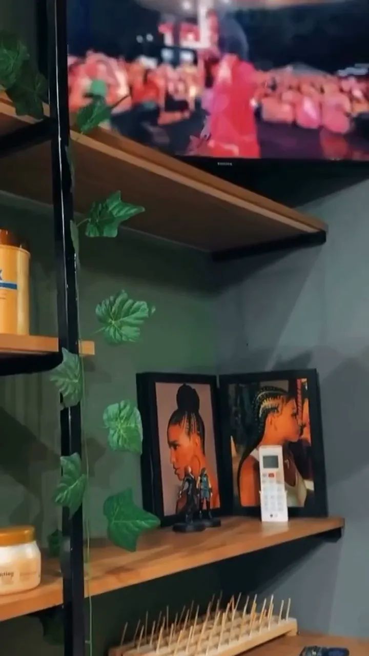 Prateleiras do estúdio com produtos, plantas e quadros de penteados afro