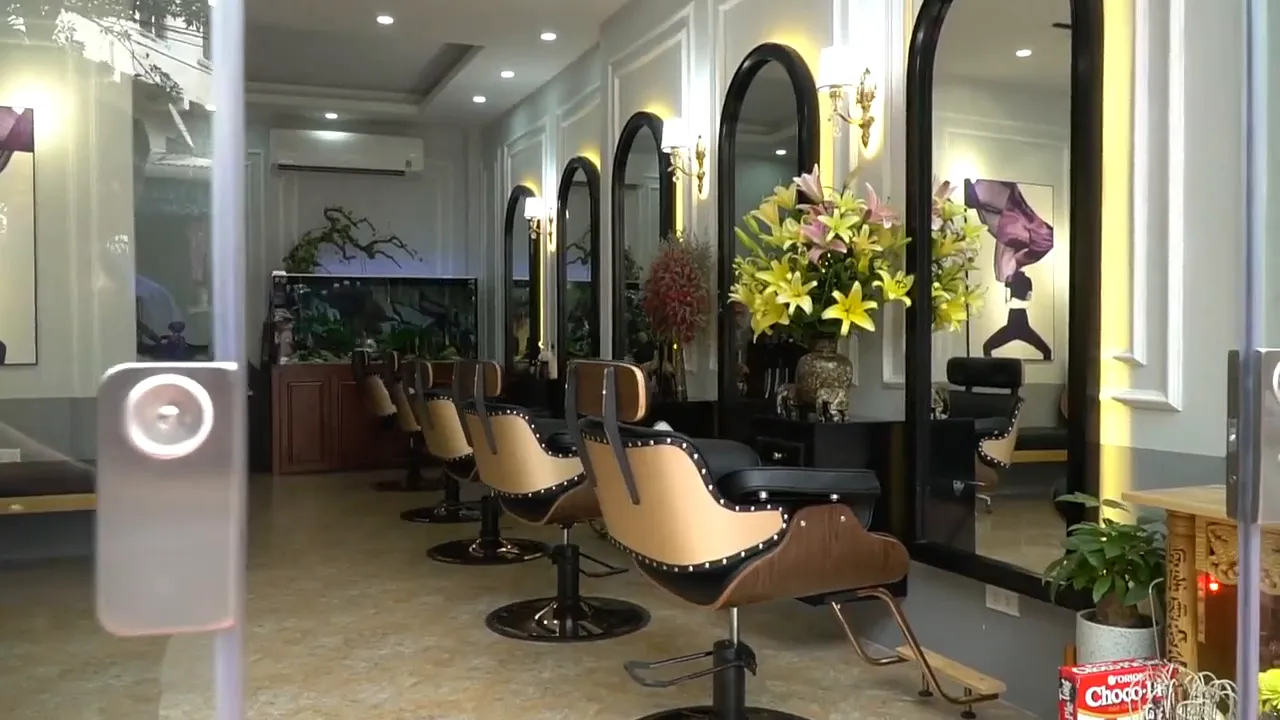 Salão de beleza visto por dentro, com espelhos em arco, cadeiras e arranjos de flores